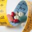 weight loss and diet pills surrounded by measuring tape