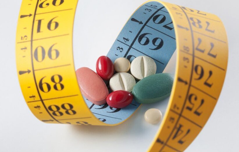 weight loss and diet pills surrounded by measuring tape